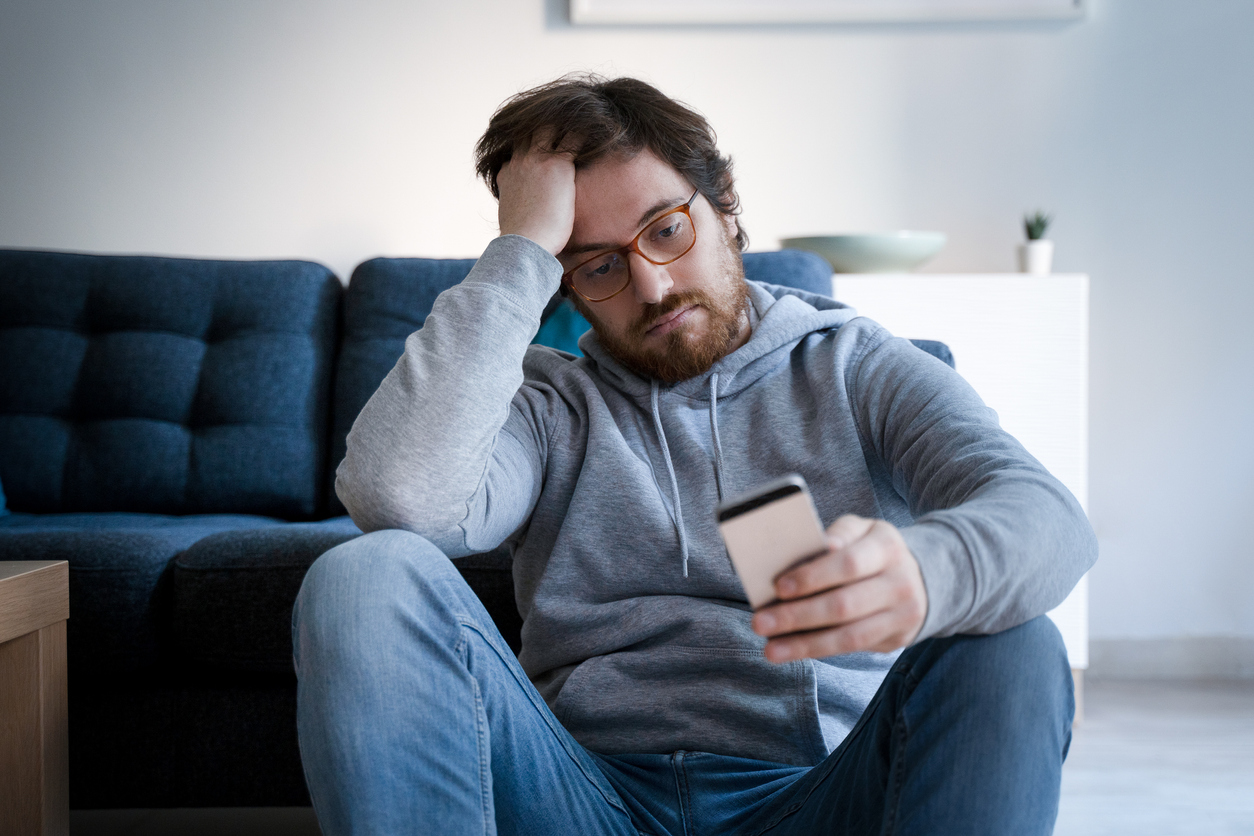 Sad young person looking at iPhone