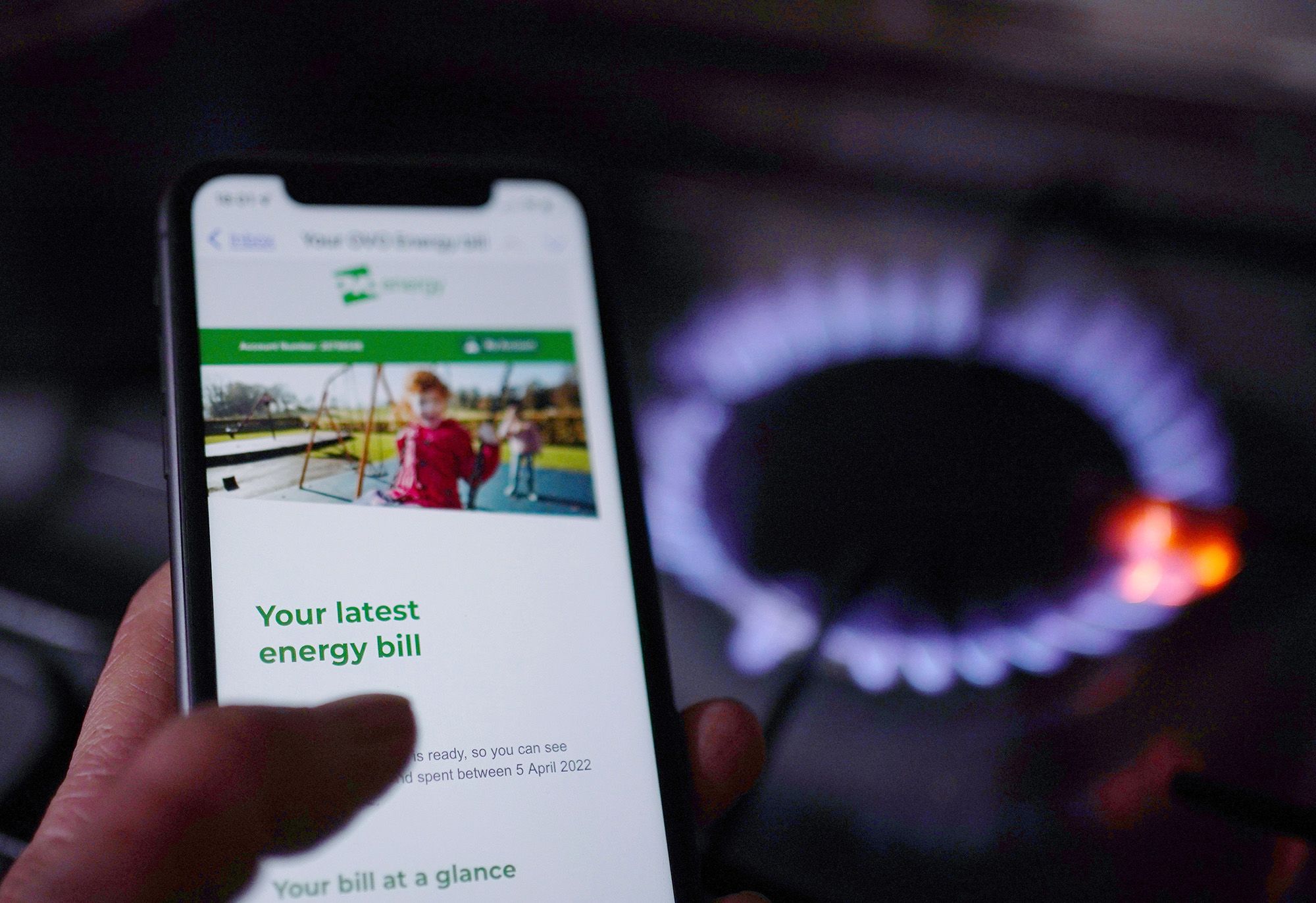 Energy bills on phone screen next to a cooker
